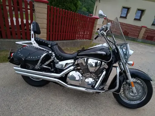 Błyszczący, czarny motocykl Honda VTX 1300 z sakwami i oparciem. Dane techniczne tego klasyka są imponujące.