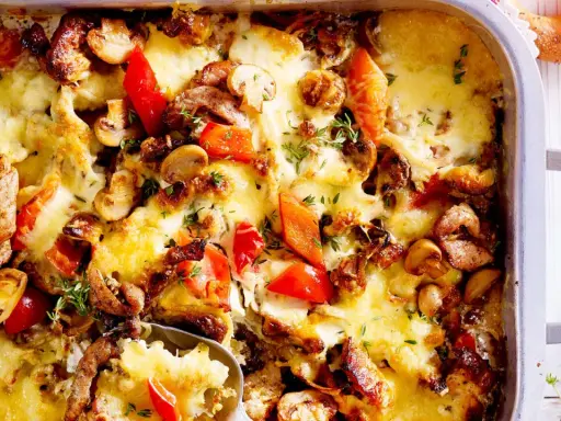 Herzhafter Gyros Auflauf mit geschmolzenem Käse, Pilzen und Paprika, garniert mit frischen Kräutern.