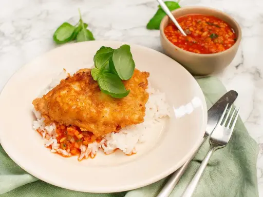 Krispig kyckling piccata serverad på ris med en smakrik tomatsås och färsk basilika. En härlig måltid!
