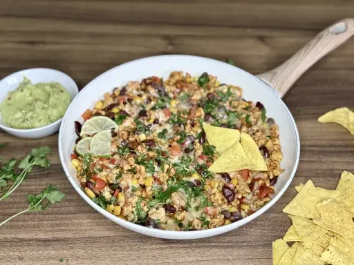 Pyszny kurczak po meksykańsku z fasolą, kukurydzą i serem, podany z guacamole i nachos.