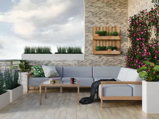 Przytulny balkon w bloku z szarą sofą, drewnianym stolikiem i kwitnącym bluszczem. Idealne miejsce na relaks po myciu balkonu w bloku.