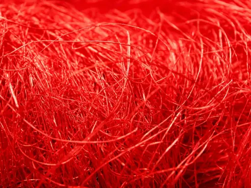 Un groviglio di fili rossi vibranti, una **fibra artificiale** che ricorda un nido intricato o capelli mossi dal vento.