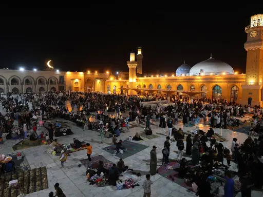 Menschen versammeln sich nachts auf einem Platz vor einer Moschee, um die Qadr Nacht zu begehen.