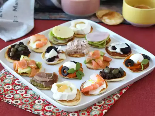 Plateau de blinis garnis de crevettes, saumon, fromage de chèvre, tapenade, jambon et autres délices.