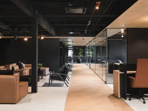 Un espace de travail innovant avec des canapés en cuir, des chaises modernes et des bureaux vitrés.