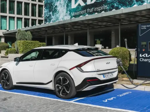 Un coche eléctrico blanco Kia EV6 cargando en un punto Kia Charge. Merece la pena un coche eléctrico por su tecnología y futuro.