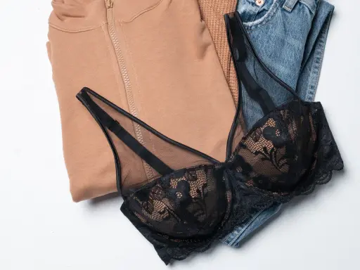 Un reggiseno di pizzo nero adagiato su jeans e felpa color cammello. Pensando a ogni quanto si cambia il reggiseno, questo è un capo che merita cura.