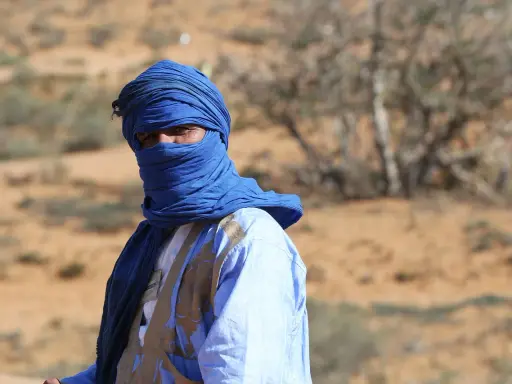 Ein Mann in traditioneller blauer Kleidung und Turban blickt aus der Wüste. Sind Marokkaner Araber? Ja, viele Marokkaner sind Araber.