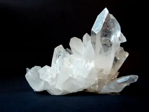 Un grappolo di cristalli di quarzo trasparenti e luminosi su sfondo scuro. Questo è un esempio di che cos'è il quarzo, un minerale comune e versatile.