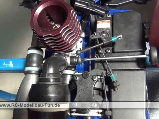 Nahaufnahme eines Nitromethan-Autos, bei dem eine Hand mit einem Schraubendreher an der Mechanik arbeitet.