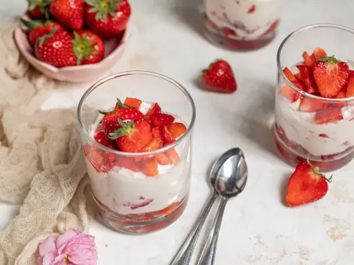 Erfrischendes Erdbeer Quark Dessert in Gläsern, garniert mit frischen Erdbeeren. Ein leichter Genuss für warme Tage.