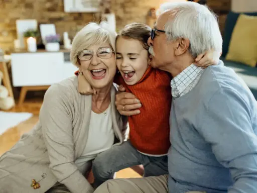 Abuelos riendo y abrazando a su nieta. Un momento tierno que demuestra la alegría de los padres que dejan a sus hijos con los abuelos.