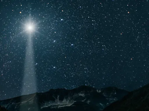 Jasna gwiazda betlejemska świeci na nocnym niebie nad górami, wskazując drogę.