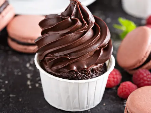 Gourmandise chocolatée : un cupcake avec ganache montée, macarons et framboises. Idéal pour la conservation ganache montée frigo.
