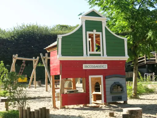Parque infantil en Holanda con casita de panadería, columpios y tobogán. Ideal para que los niños jueguen y se diviertan.