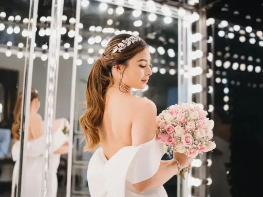 Novia con peinados de novia recogidos elegantes, tiara brillante y ramo de rosas.