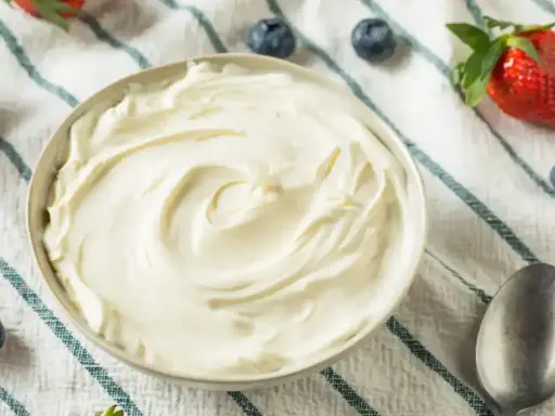 Un bol de chantilly mascarpone onctueuse, garni de fraises et de myrtilles. Parfait pour un dessert léger.