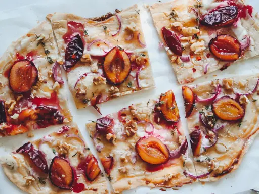 Flammkuchen mit Pflaumen, Zwiebeln und Walnüssen. Ein köstlicher Flammkuchen Belag, der süß und herzhaft kombiniert.