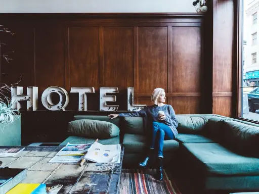 Kobieta siedzi na kanapie w hotelu, zastanawiając się, ile zarabia technik hotelarstwa.