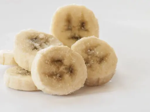 Ein Haufen gefrorener Bananenscheiben, bereit zum Einfrieren für Smoothies oder Desserts.