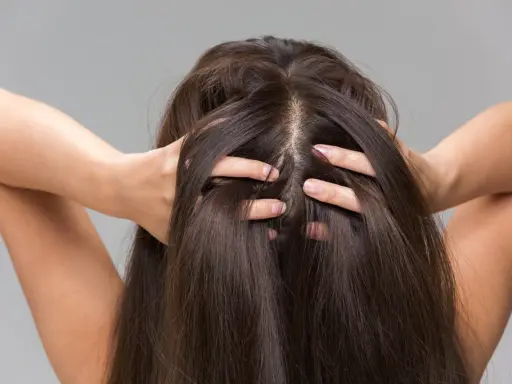 Une femme se touche les cheveux, montrant comment hydrater son cuir chevelu pour des cheveux sains et brillants.