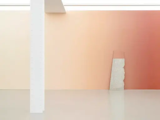 A gallery wall features a stunning gradient in art, transitioning from soft peach to warm coral. A rough stone slab leans against it.