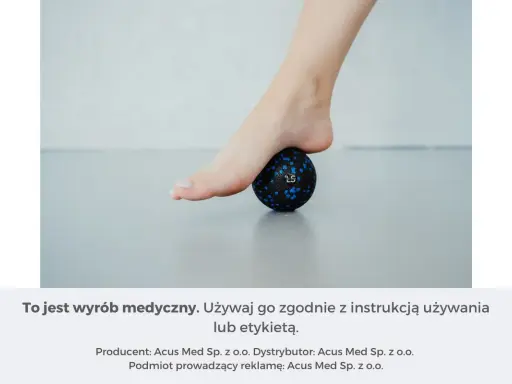Rolowanie stopy na małej, czarnej piłeczce z niebieskimi kropkami. Pomaga rozluźnić mięśnie.