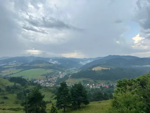 Widok na dolinę z wioską i górami w tle, chmury nad przełęczą pod Tokarnią.