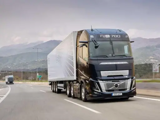 Camión Volvo FH Aero 780 negro con remolque blanco avanza por una carretera montañosa.