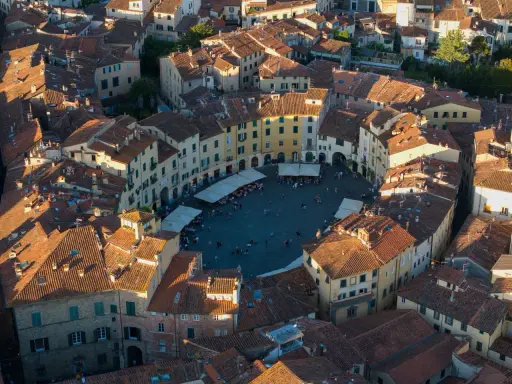 Vista aerea di Piazza dell'Anfiteatro a Lucca, perfetta per un weekend indimenticabile tra tetti rossi e vita cittadina.