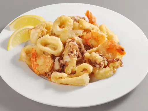 Un invitante piatto di frittura di pesce, con anelli di calamari dorati e gamberi croccanti, guarnito con spicchi di limone fresco.