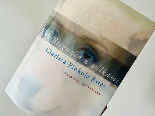 Książka "Biegnąca z wilkami" Clarissy Pinkoli Estés, światowy bestseller, z fragmentem oka na okładce.