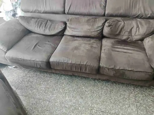 Divano marrone con cuscini un po' affossati, pronti per rifare imbottitura cuscini divano e ridargli vita.