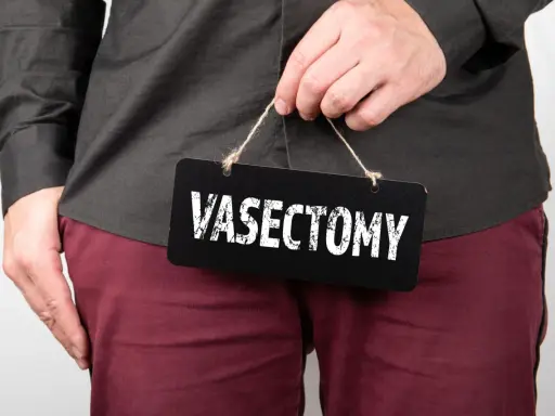 Mężczyzna trzyma tabliczkę z napisem "VASECTOMY". Czy po wazektomii można mieć dzieci? To pytanie nurtuje wielu.