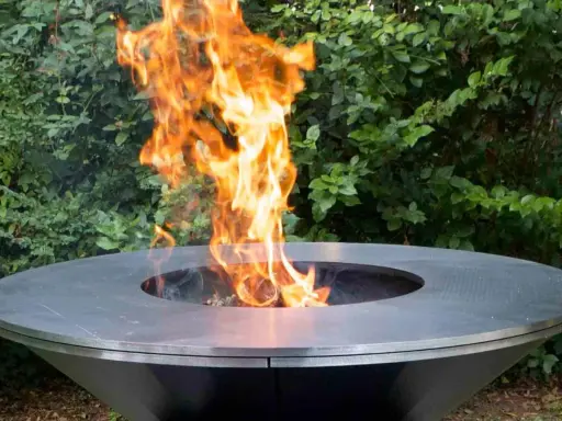 Un moderno braciere da giardino, con fiamme vivaci che danzano al centro, crea un'atmosfera accogliente.
