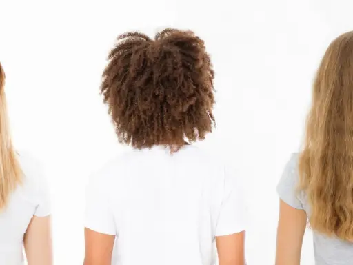 Drei Frauen von hinten: glattes, gefärbtes Haar; lockiges Haar mit hoher Porosität; welliges, blondes Haar.