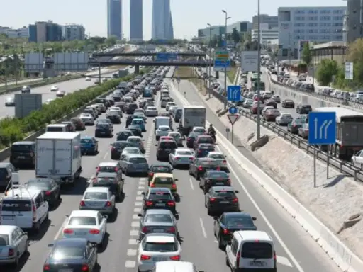 Congestión vehicular en una autopista, reflejo de la movilidad urbana. Coches y camiones detenidos en múltiples carriles bajo un cielo despejado.