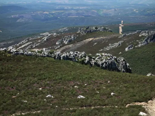 Paisaje rocoso y verde en la sierra de la Culebra, con vegetación baja y un camino serpenteante al fondo.
