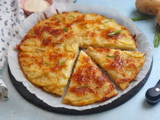 Una deliziosa torta di patate dorata e croccante, guarnita con rosmarino fresco, pronta per essere gustata.