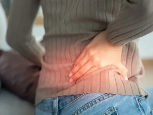Kobieta z bólem w boku, wskazującym na możliwe przyczyny pomniejszonej nerki.