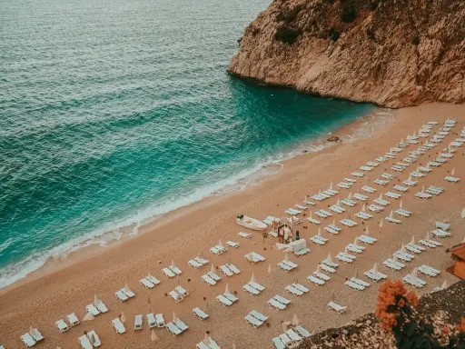 Piękna plaża z rzędami leżaków i turkusową wodą. Idealne miejsce, gdzie do Turcji na wakacje.