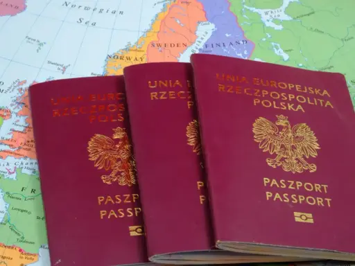 Trzy polskie paszporty leżą na mapie Europy. Czy do Grecji potrzebny jest paszport? Tak, jeśli podróżujesz spoza strefy Schengen.