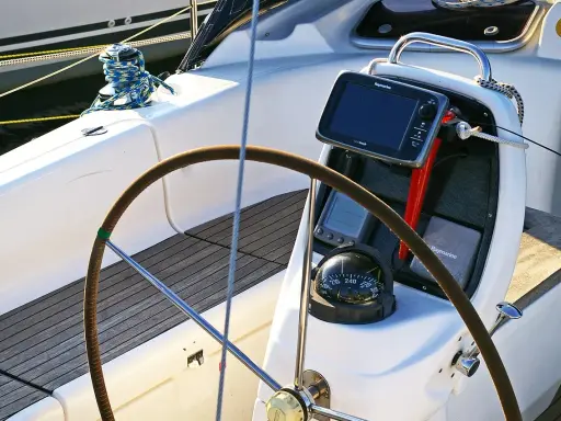 Cockpit de voilier avec barre, compas et écran Raymarine. Idéal pour un gps marine gratuit pour Android.