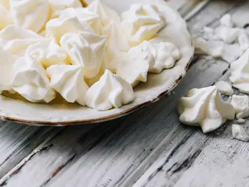 Douceur aérienne : des meringues comme celles de Cyril Lignac, croustillantes à souhait, sur une assiette vintage.