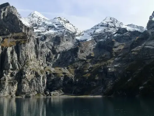 Majestatyczne Tatry Wschodnie z ośnieżonymi szczytami odbijają się w spokojnej tafli jeziora.