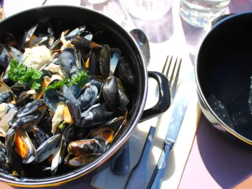 Moules marinières crémeuses, une spécialité culinaire normandie, servies dans une cocotte avec du pain frais.