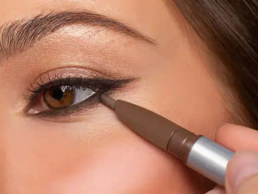 Ojo marrón con delineado invertido, aplicando lápiz marrón en la línea de agua inferior para un look dramático.