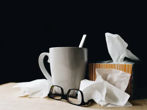 Kubek z herbatą, chusteczki i okulary. Urlop L4 nie zawsze jest wypoczynkiem.