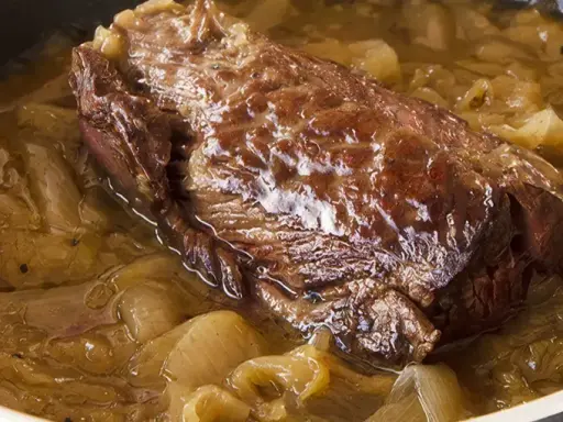 Une succulente buche d'onglet mijote dans une sauce aux oignons caramélisés, prête à être dégustée.