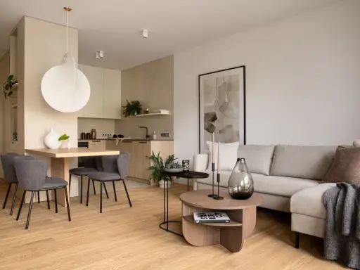 Beżowy salon inspiracje: przytulna przestrzeń z szarą sofą, drewnianym stołem i nowoczesną kuchnią.